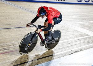 Female track cyclist in team Ontario kit smiling mid sprint
