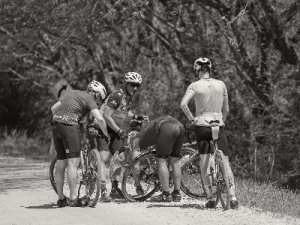 Group of gravel cyclists help with maintenance on a ride