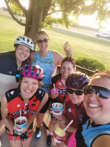 Jennifer Hare and a group of cyclists smiling in the sunset of a successful ride