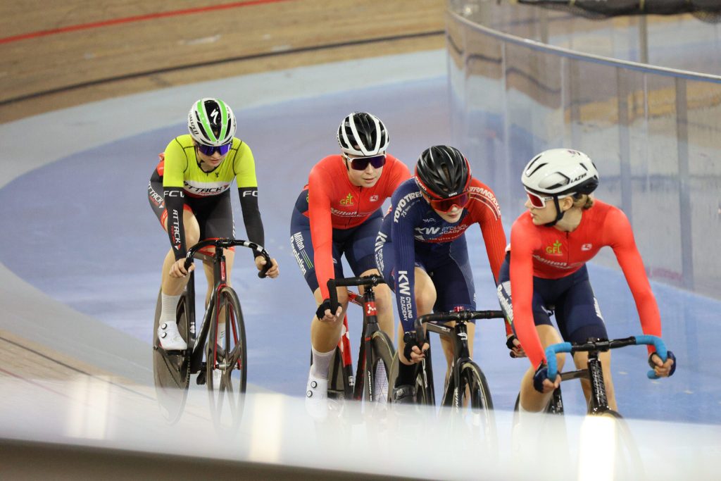 Group of female youth track cyclists draft during a race